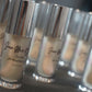 Row of skincare bottles with visible labels on a reflective surface